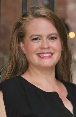 Professional headshot portrait of real estate agent Nicole Bevington smiling, wearing a black top.